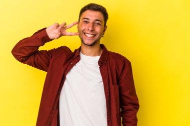 Sarı arka planda izole edilmiş dövmeleri olan genç beyaz adam dans ediyor ve eğleniyor..