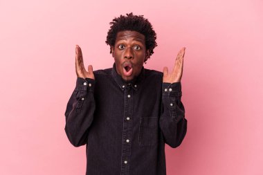 Genç Afrikalı Amerikalı, pembe arka planda izole edilmiş. Şaşırmış ve şok olmuş..