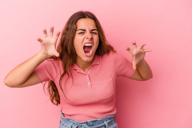 Pembe arka planda izole edilmiş genç beyaz kadın pençelerini kedi taklidi yaparken gösteriyor, agresif bir hareket..