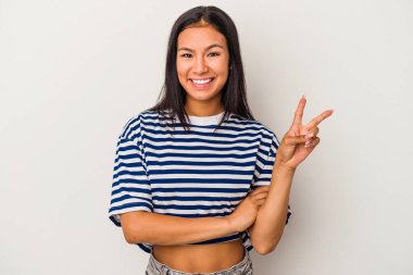 Beyaz arka planda izole edilmiş genç Latin kadın iki numarayı parmaklarıyla gösteriyor..