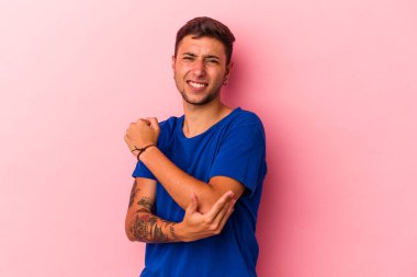 Dövmeleri olan beyaz bir genç adam sarı arka planda izole edilmiş dirsek masajı yapıyor, kötü bir hareketin ardından acı çekiyor..