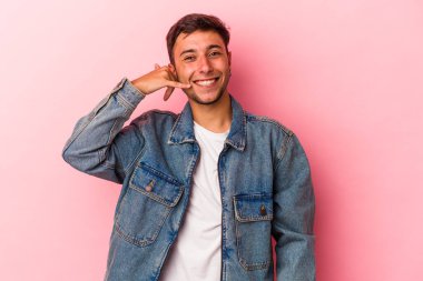 Sarı arka planda izole edilmiş dövmeleri olan genç beyaz bir adam parmakları olan bir cep telefonu hareketi gösteriyor..