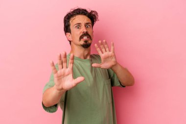 Pembe arka planda izole genç beyaz adam yakın bir tehlike nedeniyle şoka uğruyor.