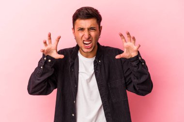 Sarı arka planda izole edilmiş dövmeleri olan genç, beyaz bir adam gergin elleriyle çığlık atıyor..