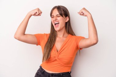 Beyaz arka planda izole genç beyaz kadın zafer kazandıktan sonra yumruğunu kaldırıyor, kazanan konsept..