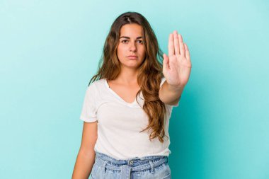 Mavi arka planda izole edilmiş genç beyaz kadın elini uzatmış, dur işareti göstererek seni engelliyor..