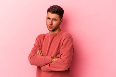 Sarı arka planda izole edilmiş beyaz dövmeli genç adam alaycı bir ifadeyle kameraya bakıyor..