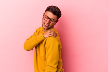 Sarı arka planda izole edilmiş, omuz ağrısı olan beyaz dövmeli genç bir adam..