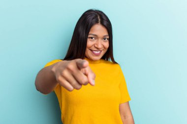 Genç Venezuelalı bir kadın, mavi arka planda soyutlanmış, mutlu bir şekilde gülümsüyor..