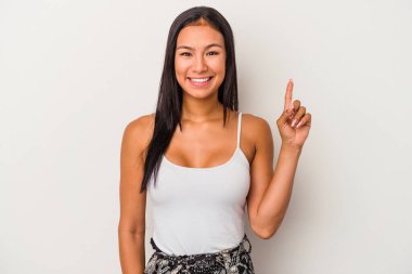 Beyaz arka planda izole edilmiş genç Latin kadın bir numarayı parmağıyla gösteriyor..