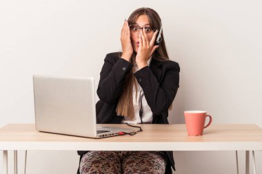 Beyaz arka planda yalnız başına seyahat eden beyaz tenli genç bir kadın korkmuş ve gergin parmaklarıyla göz kırpıyor..