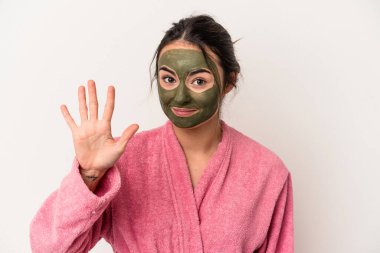 Young caucasian woman wearing a facial mask isolated on white background smiling cheerful showing number five with fingers.