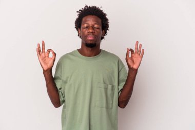 Genç Afrikalı Amerikalı erkek, beyaz arka planda izole edilmiş yoğun bir günün ardından dinleniyor, yoga yapıyor..