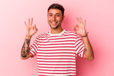 Sarı arka planda izole edilmiş beyaz dövmeli genç bir adam. Neşeli ve kendinden emin..