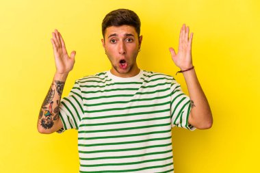 Sarı arka planda izole edilmiş dövmeleri olan genç beyaz adam şaşırdı ve şok oldu..