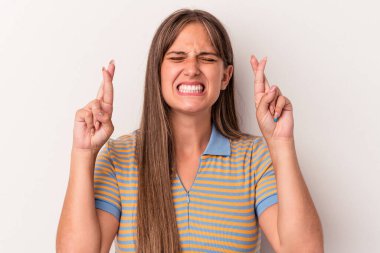 Beyaz arka planda izole genç beyaz kadın şans dilemek için parmaklarını çapraz