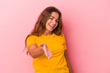 Pembe arka planda izole edilmiş beyaz bir kadın. Kameraya elini uzatıp selam veriyor..