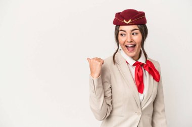 Young caucasian stewardess woman isolated on white background points with thumb finger away, laughing and carefree.