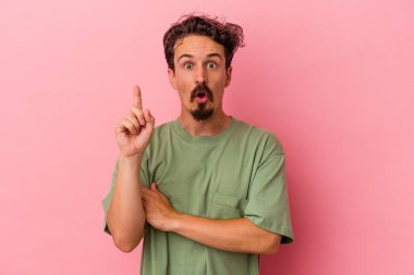 Pembe arka planda soyutlanmış genç beyaz bir adam. Harika bir fikri var, yaratıcılık kavramı..