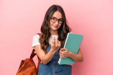Young caucasian student woman isolated on pink background pointing with finger at you as if inviting come closer.