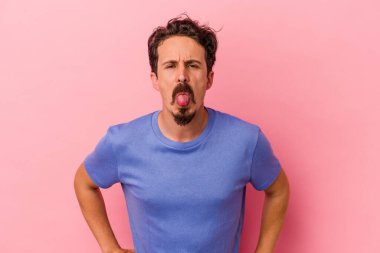 Genç, beyaz bir adam pembe arka planda izole edilmiş komik ve dost canlısı bir dil kullanıyor..