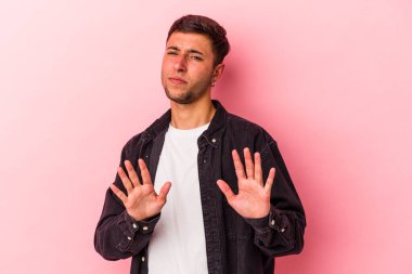 Sarı arka planda dövmeleri olan beyaz bir genç adam tiksinti belirtisi gösteren birini reddediyor..