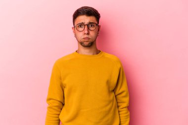 Sarı arka planda izole edilmiş dövmeleri olan beyaz genç bir adam yanakları patlatıyor, yorgun bir ifade takınıyor. Yüz ifadesi kavramı.