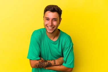 Sarı arka planda izole edilmiş dövmeleri olan beyaz bir adam gülüyor ve eğleniyor..