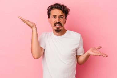 Kafkasyalı genç adam pembe arka planda izole edilmiş. Kafası karışmış ve omuz silkiyor. Kopya alanını tutmak için..