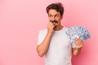 Pembe arka planda izole edilmiş banknotlar tutan beyaz bir adam rahatça fotokopi odasına bakan bir şey düşünüyor..