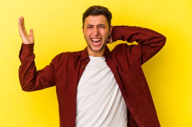 Sarı arka planda izole edilmiş dövmeleri olan genç beyaz bir adam öfkeyle bağırıyor..