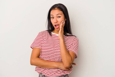 Beyaz arka planda izole edilmiş genç Latin kadın yüksek sesle bağırıyor, gözleri açık ve elleri gergin tutuyor..