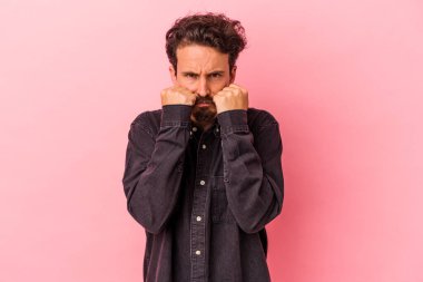 Pembe arka planda izole edilmiş genç beyaz bir adam bir tartışma yüzünden yumruk, öfke, kavga ve boks atıyor..