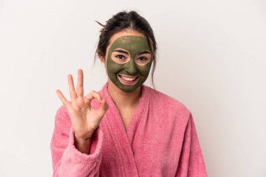 Young caucasian woman wearing a facial mask isolated on white background cheerful and confident showing ok gesture.
