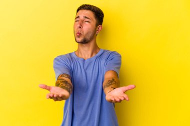 Sarı arka planda izole edilmiş, dudakları kıvrılmış ve hava öpücüğü yollamak için avuç içi tutan beyaz bir adam..