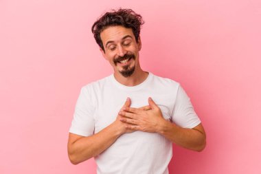Pembe arka planda izole edilmiş genç beyaz bir adam, dostane bir ifadeye sahip, avuçlarını göğsüne bastırıyor. Aşk konsepti.