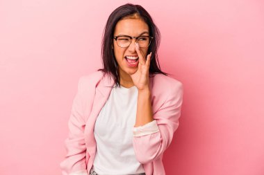 Pembe arka planda izole edilmiş genç Latin kadın heyecanla bağırıyor..