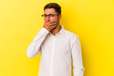 Sarı arka planda izole edilmiş dövmeleri olan, elleri endişeli görünen genç beyaz bir adam..