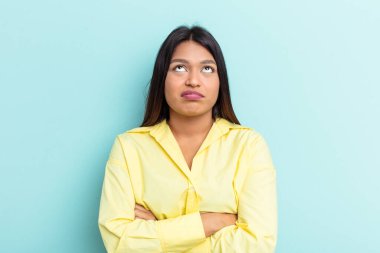 Genç Venezuelalı kadın mavi arka planda izole edilmiş. Tekrarlanan bir görevden yorulmuş..