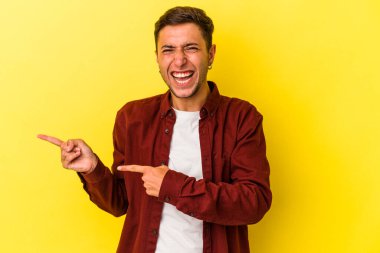 Sarı arka planda izole edilmiş beyaz dövmeli genç bir adam işaret parmağıyla fotokopi alanını işaret ederek heyecan ve arzusunu ifade ediyor..