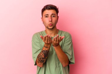 Sarı arka planda izole edilmiş, dudakları kıvrılmış ve hava öpücüğü yollamak için avuç içi tutan beyaz bir adam..