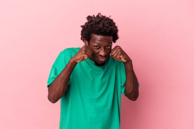 Genç Afro-Amerikalı bir adam pembe arka planda izole edilmiş. Bir tartışma yüzünden yumruk atıyor, sinirleniyor, kavga ediyor..