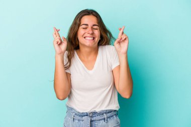 Genç beyaz kadın, mavi arka planda izole edilmiş şans dilemek için şans diliyor.