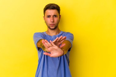 Sarı arka planda izole edilmiş dövmeleri olan beyaz genç bir adam elini uzatmış, dur işareti göstererek seni engelliyor..