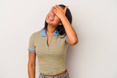 Beyaz arka planda soyutlanmış genç Latin bir kadın elleriyle gözlerini kapatıyor, gülümseyerek bir sürpriz bekliyor..