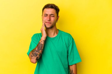 Sarı arka planda izole edilmiş dövmeleri olan beyaz bir genç adam. Güçlü bir diş ağrısı, azıdişi ağrısı var..