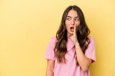 Sarı arka planda izole edilmiş genç beyaz kadın gizli bir sıcak fren haberi veriyor ve yana bakıyor.
