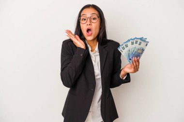 Elinde banknotlar tutan genç Latin kadın beyaz arka planda izole edilmiş kahve şaşırmış ve şok olmuştu..