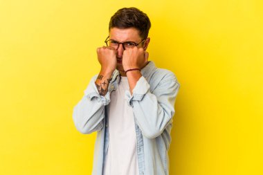 Sarı arka planda izole edilmiş dövmeleri olan genç beyaz bir adam bir tartışma yüzünden yumruk, öfke, kavga atıyor, boks yapıyor..