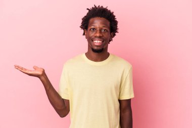 Pembe arka planda izole edilmiş genç Afro-Amerikalı bir adam bir avuç içinde fotokopi alanı ve belinde başka bir el tutuyor..